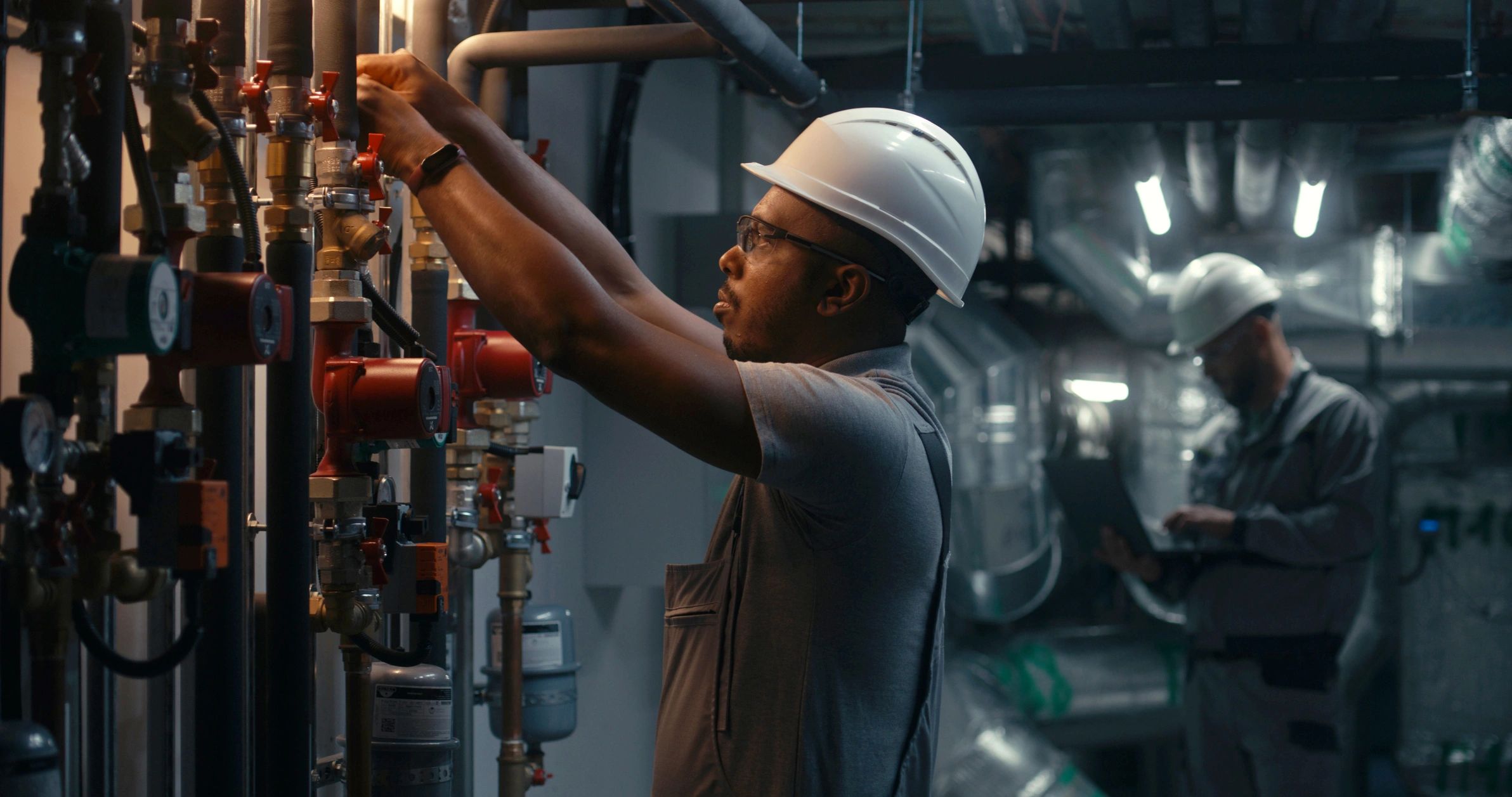 Commercial technician checking mechanical equipment during service call