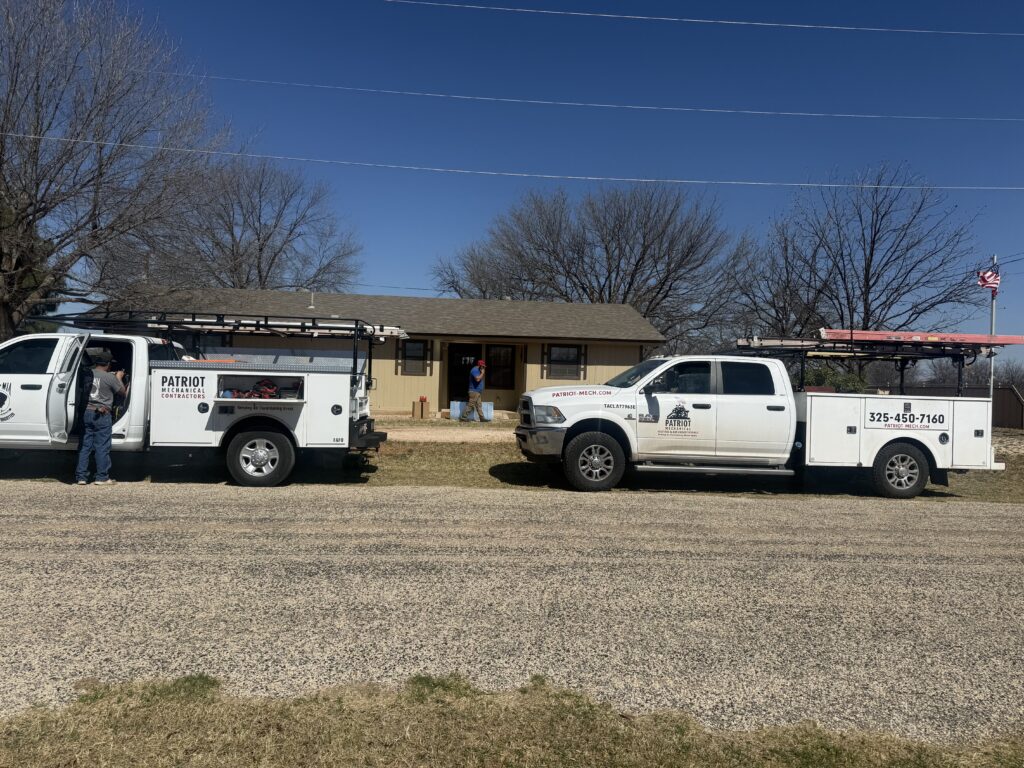 Two Patriot Mechanical Contractor trucks in front of a customers house.